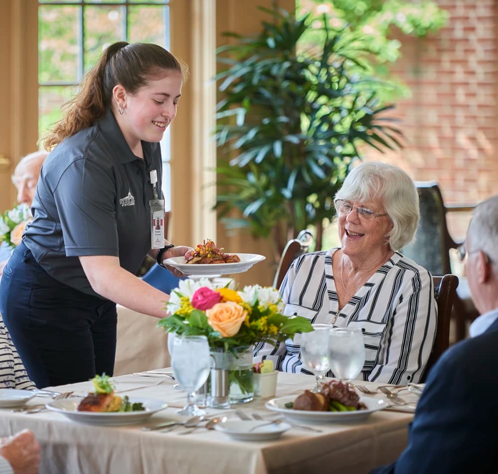 Woman serving a meal to residents at table