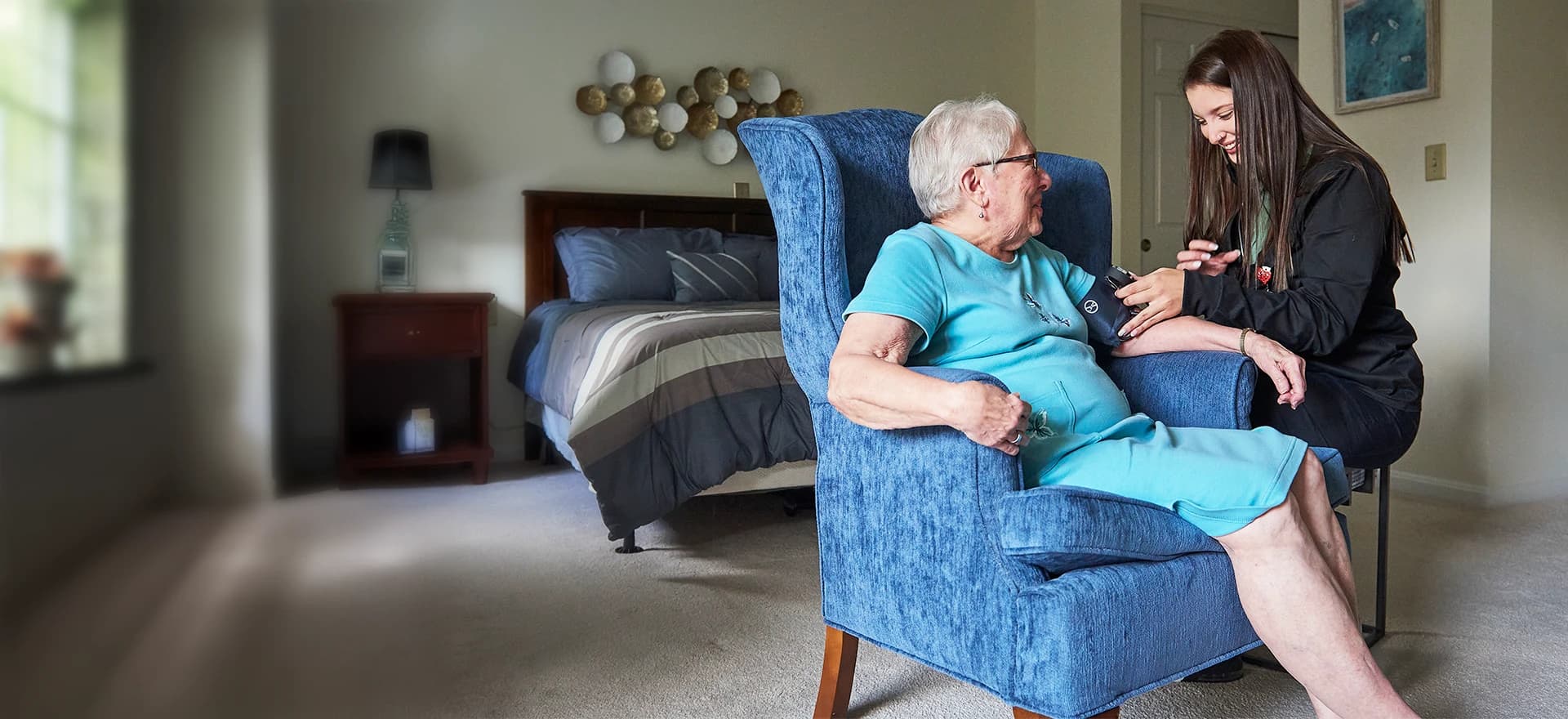 Woman and care giver taking blood pressure - wide view